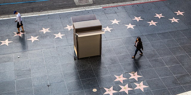 FILE- People walking along the Hollywood Walk of Fame on a sunny day in Los Angeles. There are more than 2000 tiles at the walk of fame to honor the stars.