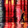 A man is silhouetted as he crosses a rain-covered street on a cold, windy night in Kansas City, Missouri, Nov. 26, 2019.