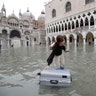 A tourist pushes her floating luggage in a flooded St. Mark's Square, in Venice, Nov. 13, 2019. 