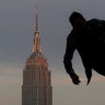 A skateboarder goes down a ramp as the sun sets on the Empire State Building in New York City, Nov. 10, 2019.