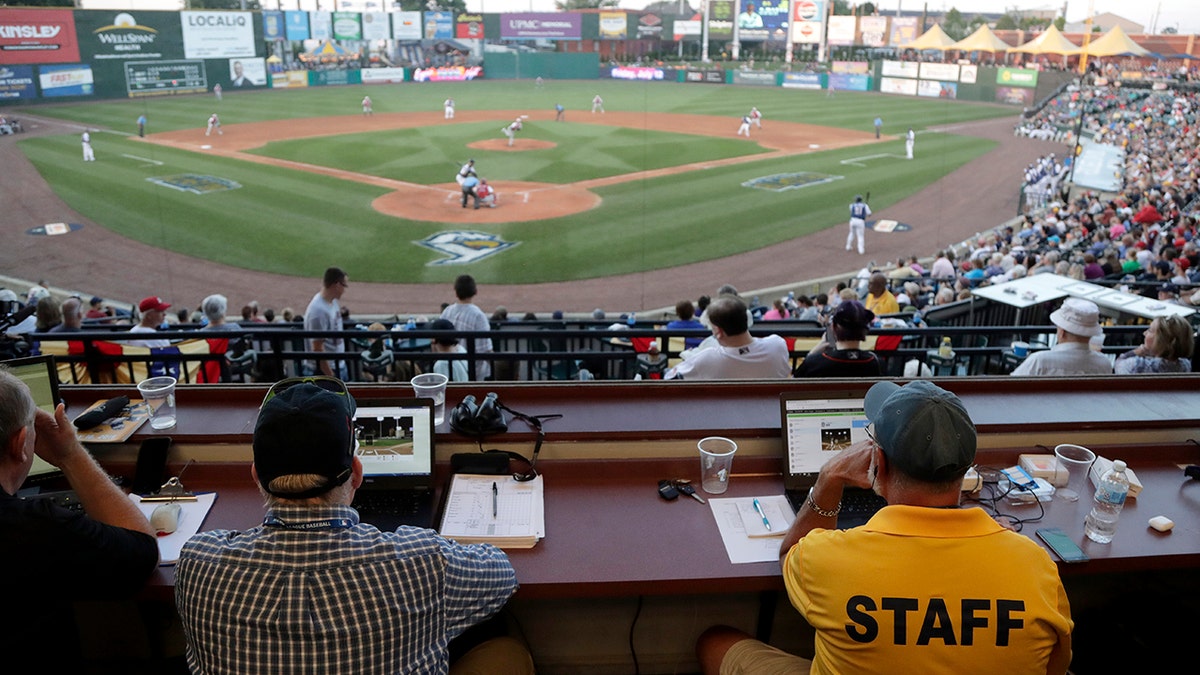FILE - In this July 10, 2019, file photo, Ron Besaw, right, operates a laptop computer as home plate umpire Brian deBrauwere, gets signals from radar with the ball and strikes calls during the fourth inning of the Atlantic League All-Star minor league baseball game in York, Pa. (AP Photo/Julio Cortez, File)