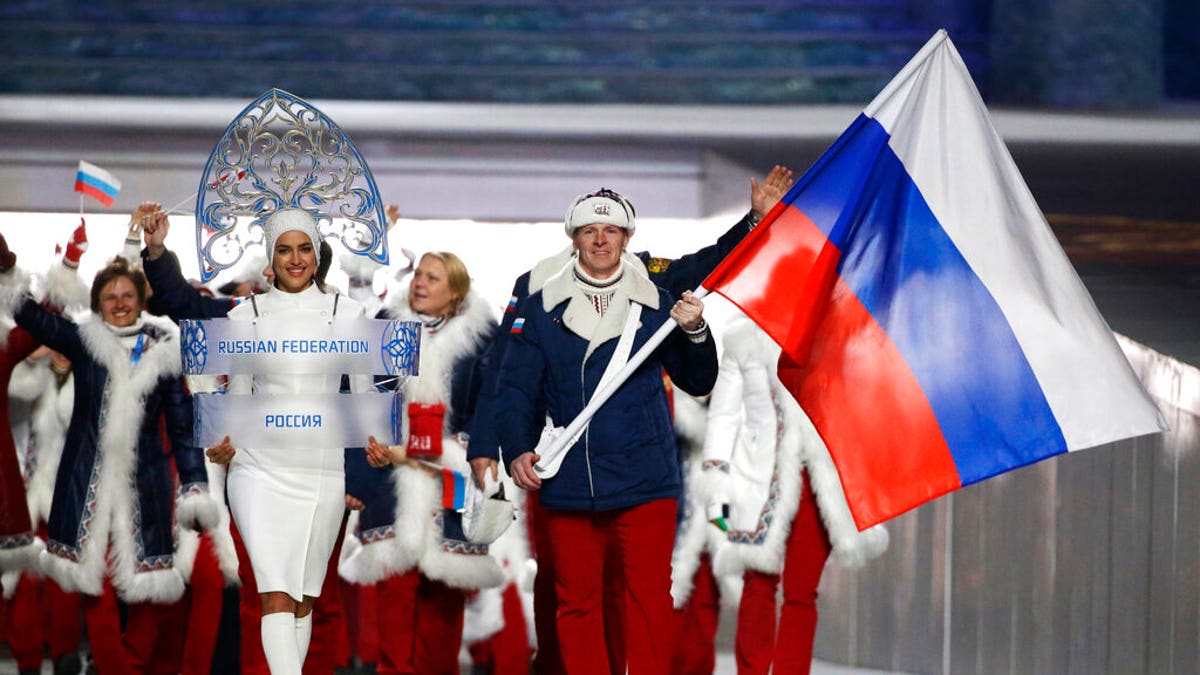 Alexander Zubkov of Russia carries the national flag as he leads the team during the opening ceremony of the 2014 Winter Olympics in Sochi, Russia. Model Irina Shayk, left, is seen carrying the Russian placard.
