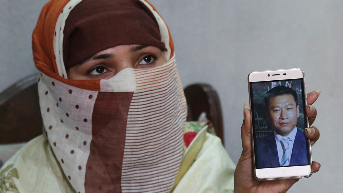 FILE - In this May 22, 2019 file photo, Sumaira a Pakistani woman, shows a picture of her Chinese husband in Gujranwala, Pakistan. Sumaira, who didn't want her full name used, was raped repeatedly by Chinese men at a house in Islamabad where she was brought to stay after her brothers arranged her marriage to the older Chinese man. (AP Photo/K.M. Chaudary, File)