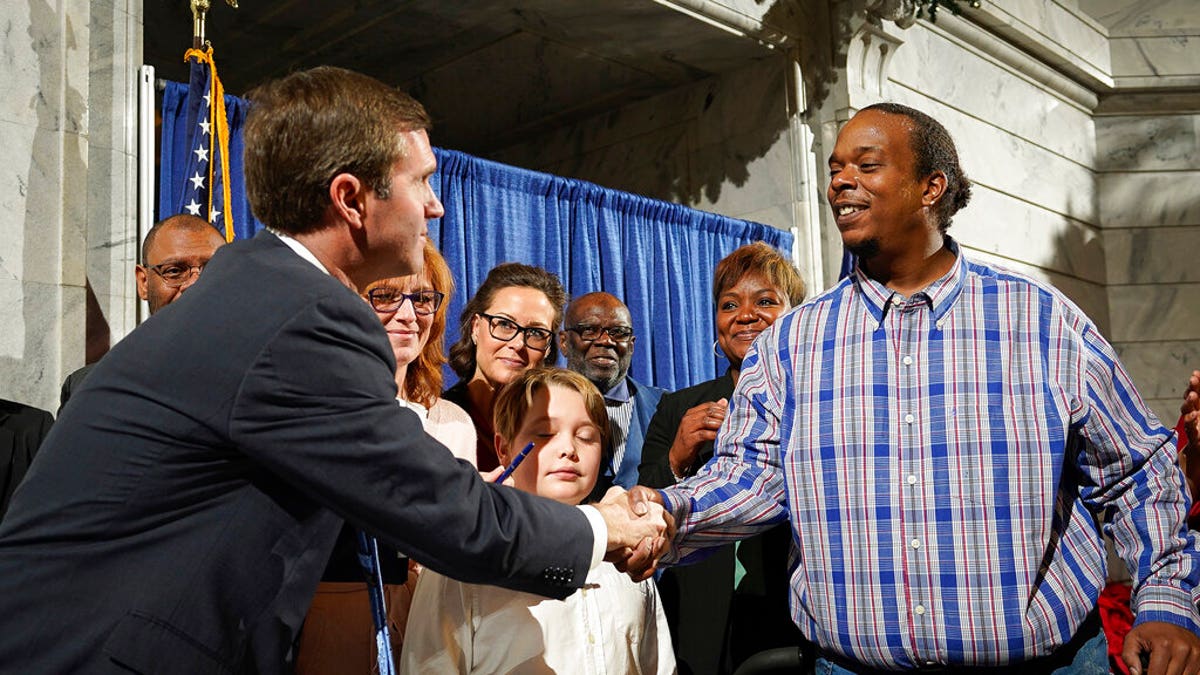 Rynn Young, of Louisville, Kentucky, shaking Beshear's hand after the signing of the executive order. (AP Photo/Bryan Woolston)