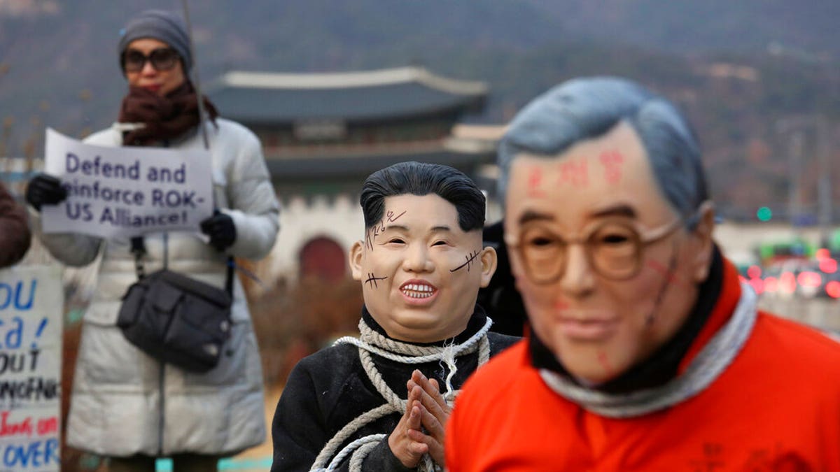 Protesters wear masks of North Korean leader Kim Jong Un and South Korean President Moon Jae-in, right, during a rally to denounce policies of Moon on North Korea near the U.S. embassy in Seoul, South Korea, Friday, Dec. 13, 2019.
