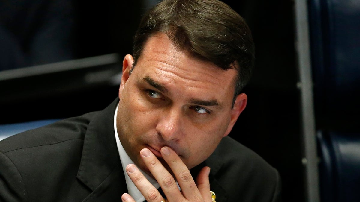 In this Oct. 22, 2019 file photo, Brazilian Sen. Flavio Bolsonaro, son of the nation's president, attends the final voting session on pension reform at the Senate in Brasilia, Brazil. Sen. Bolsonaro on Thursday accused "ill-intentioned" prosecutors of persecuting his family, one day after they searched a chocolate shop he co-owns as part of an investigation into allegedly suspicious financial movements. (AP Photo/Eraldo Peres, File)