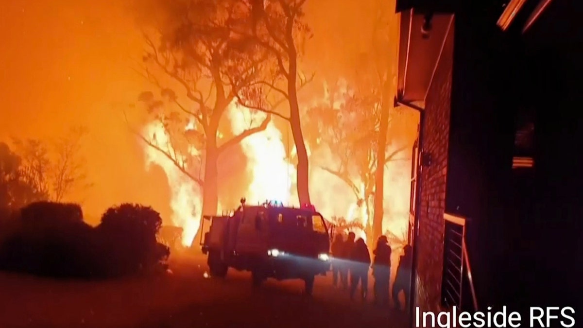 This image made from video taken on Dec. 22, 2019, and provided Dec. 25, 2019, by Ingleside Rural Fire Brigade, shows the wildfire behind an emergency vehicle near property on Hat Hill Road in Blackheath, New South Wales. Australian authorities have warned that the fires in New South Wales could fester for months, causing more angst for exhausted firefighters.(Ingleside Rural Fire Brigade via AP)