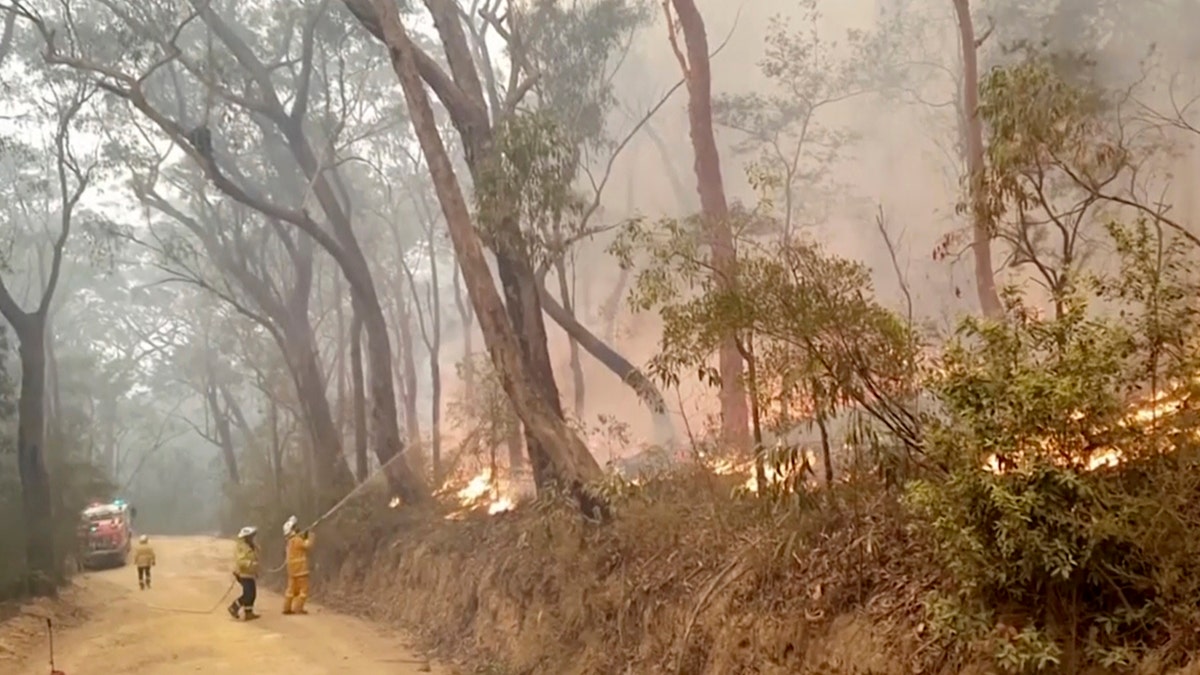 In this image made from video taken on Dec. 23, 2019, and provided Dec. 25, 2019, by Ingleside Rural Fire Brigade, fire brigade volunteers trying to tackle the fire in Kurrajong Heights, New South Wales. Australian authorities have warned that the fires in New South Wales could fester for months, causing more angst for exhausted firefighters.(Ingleside Rural Fire Brigade via AP)