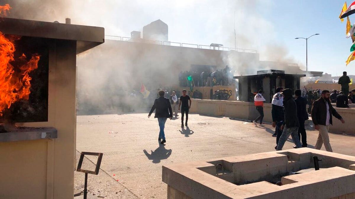Dozens of Iraqi Shiite militia supporters are seen at the U.S. embassy compound where a fire was set to a reception area, in Baghdad, Iraq, Tuesday, Dec. 31, 2019. An angry mob smashed a door and stormed inside the compound Tuesday following deadly U.S. military airstrikes on Sunday against the Kataeb Hezbollah militia in Iraq and Syria. (AP Photo/Qassim Abdul-Zahra)