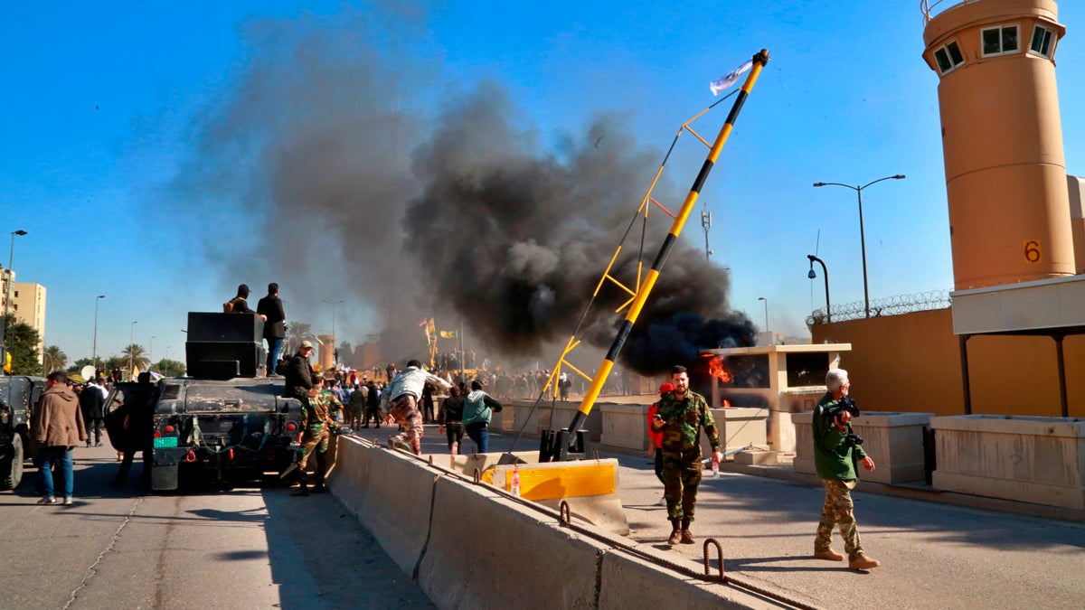 Security forces standing guard while protesters burned property in front of the U.S. Embassy compound in Baghdad on Tuesday. (AP Photo/Khalid Mohammed)