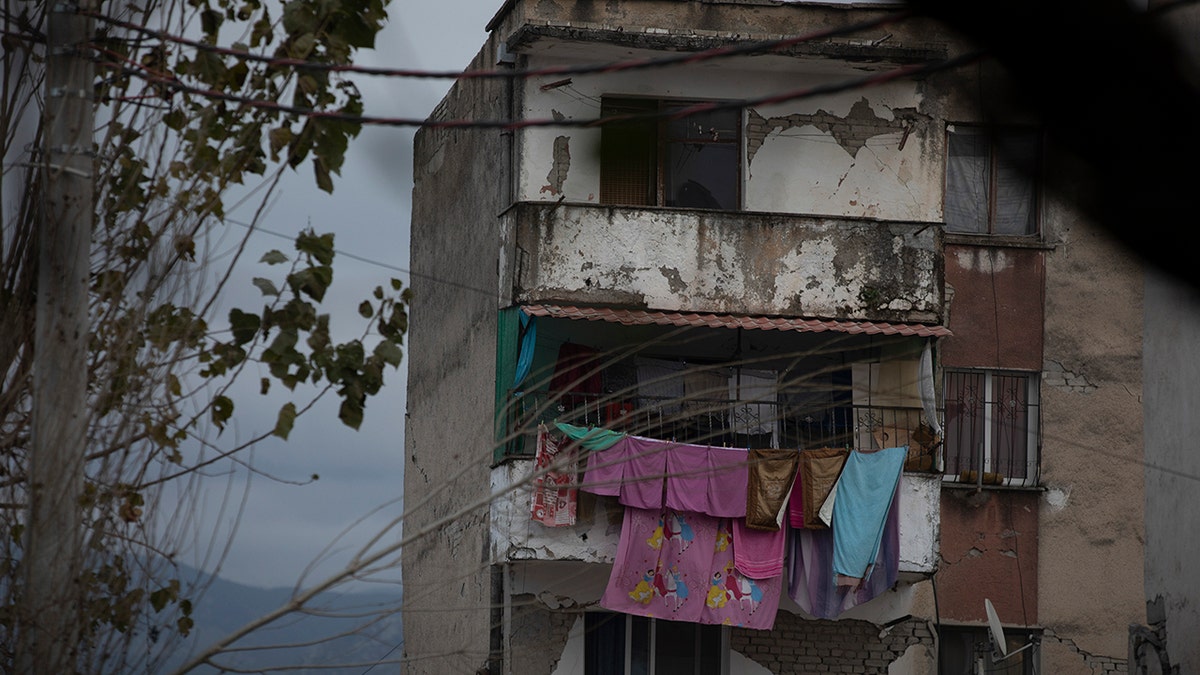 In this Wednesday, Nov. 27, 2019 photo, laundry hangs on a line from a damaged building in Thumane, western Albania following a deadly earthquake. 