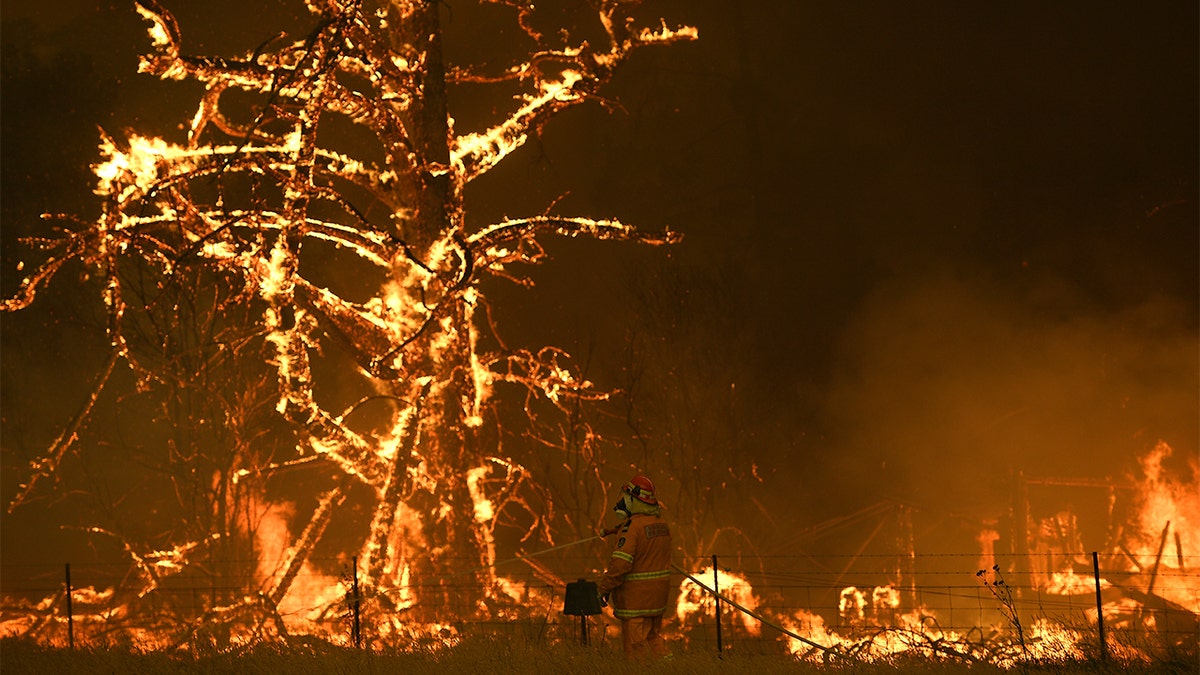 In this Saturday, Dec. 21, 2019, photo, NSW Rural Fire Service crew fight the Gospers Mountain Fire as it impacts a property at Bilpin, New South Wales state, (Dan Himbrechts/AAP Images via AP)