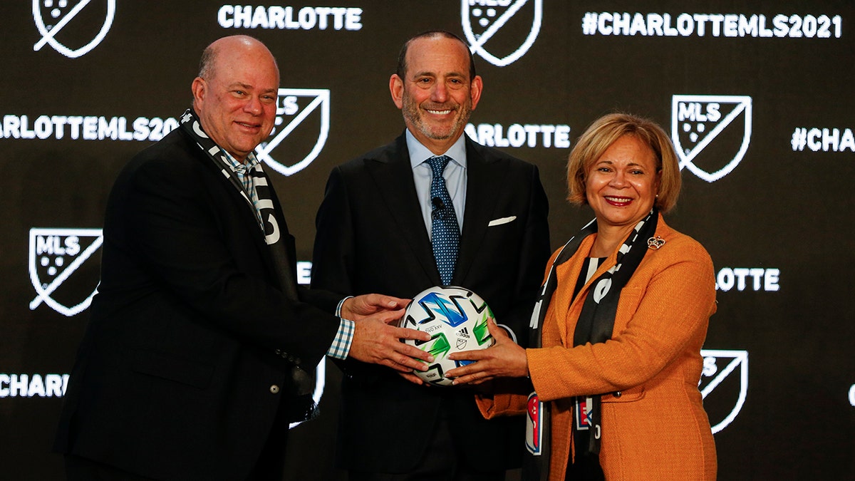 Major League Soccer Commissioner Don Garber, left, Charlotte MLS owner David Tepper, center, and Charlotte mayor Vi Lyles pose for a photo after announcing the MLS will have a team in Charlotte in 2021 at an event in Charlotte, N.C., Tuesday, Dec. 17, 2019. (AP Photo/Nell Redmond)