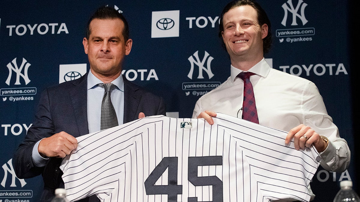 New York Yankees manager Aaron Boone, left, and pitcher Gerrit Cole hold up a jersey as Cole is introduced as the baseball club's newest player during a media availability, Wednesday, Dec. 18, 2019 in New York. The pitcher agreed to a 9-year, $324 million contract. (AP Photo/Mark Lennihan)