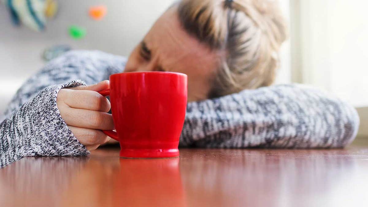 Woman with a hangover drinking a cup of coffee in the morning