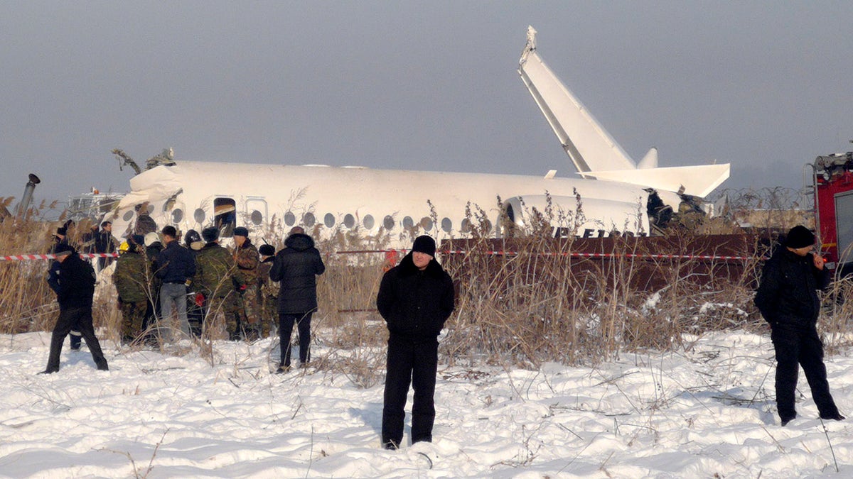 Police stand guard as rescuers assist on the site of a plane crash near Almaty International Airport, outside Almaty, Kazakhstan, Friday, Dec. 27, 2019. Almaty International Airport said the Bek Air plane crashed Friday in Kazakhstan shortly after takeoff causing numerous deaths. The aircraft had 100 passengers and crew onboard when hit a concrete fence and a two-story building shortly after takeoff. 