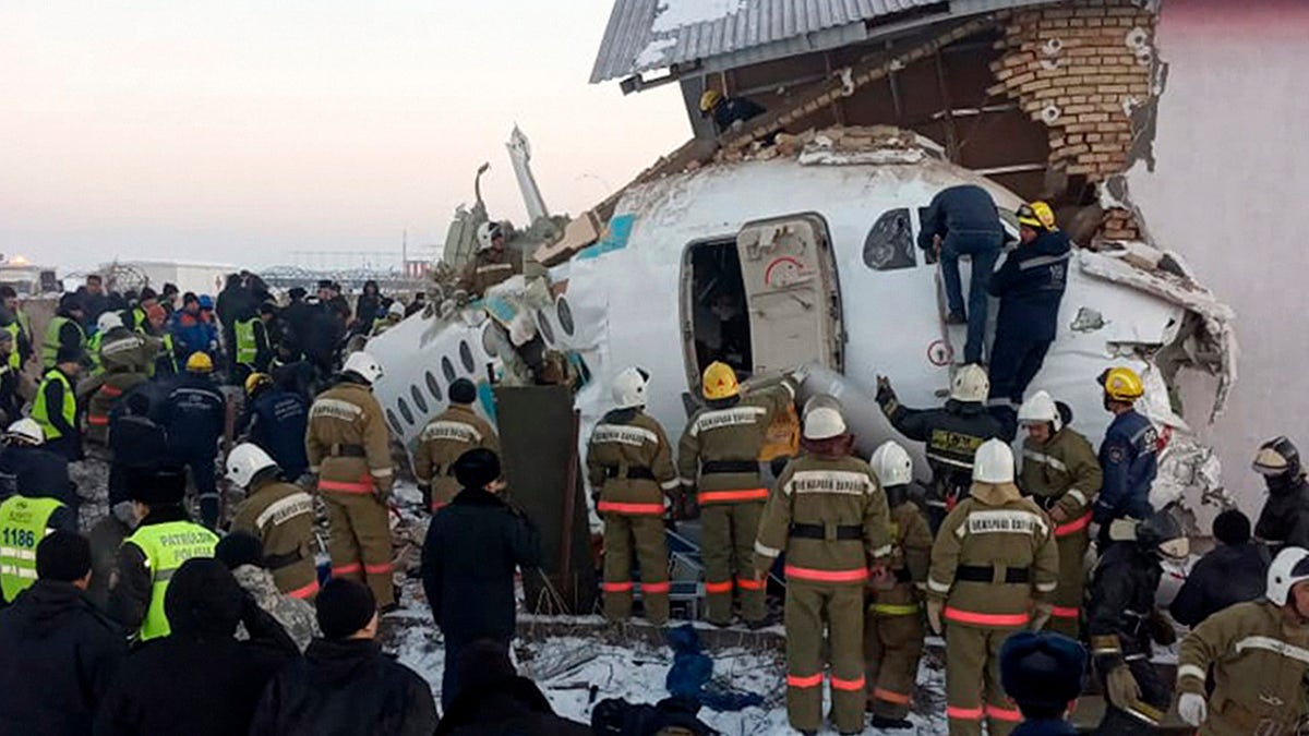 In this handout photo provided by the Emergency Situations Ministry of the Republic of Kazakhstan, police and rescuers work on the site of a plane crash near Almaty International Airport, outside Almaty, Kazakhstan, Friday, Dec. 27, 2019. Almaty International Airport said a Bek Air plane crashed Friday in Kazakhstan shortly after takeoff causing numerous deaths. The aircraft had 100 passengers and crew onboard when hit a concrete fence and a two-story building shortly after takeoff.