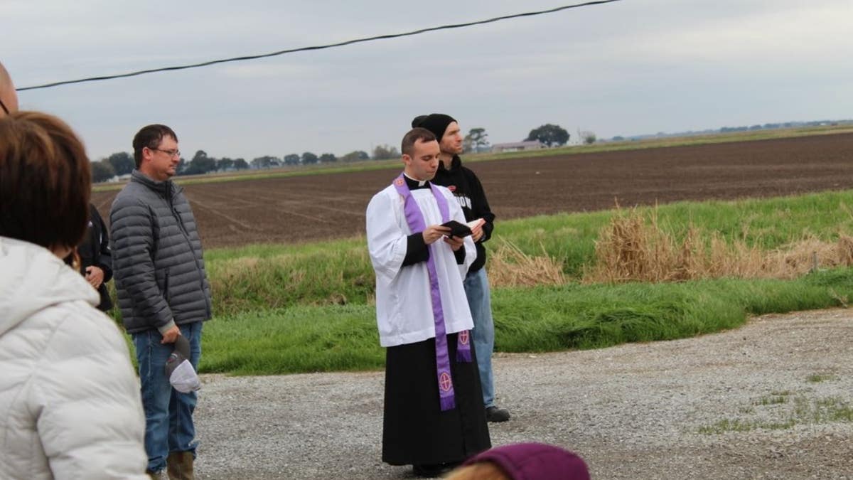 Rev. Matthew Barzare blesses 100 gallons of water on an airstrip.