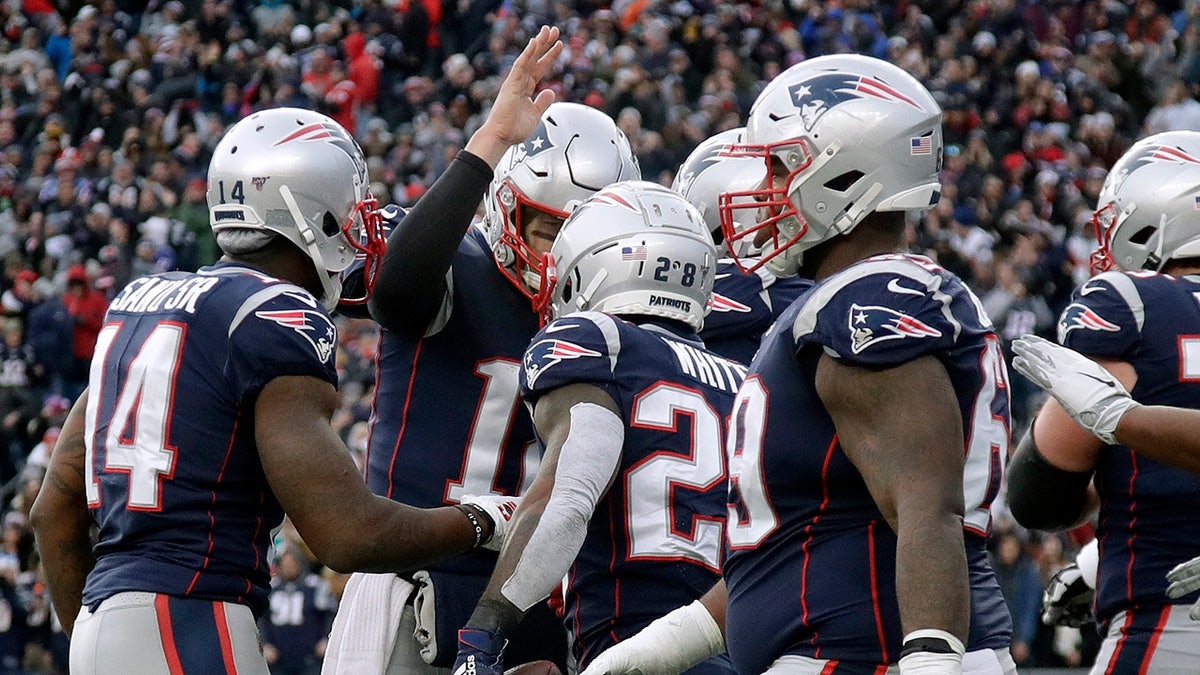 New England Patriots quarterback Tom Brady, rear, congratulates running back James White, center, on his touchdown against the Miami Dolphins in the second half of an NFL football game, Sunday, Dec. 29, 2019, in Foxborough, Massachusetts.
