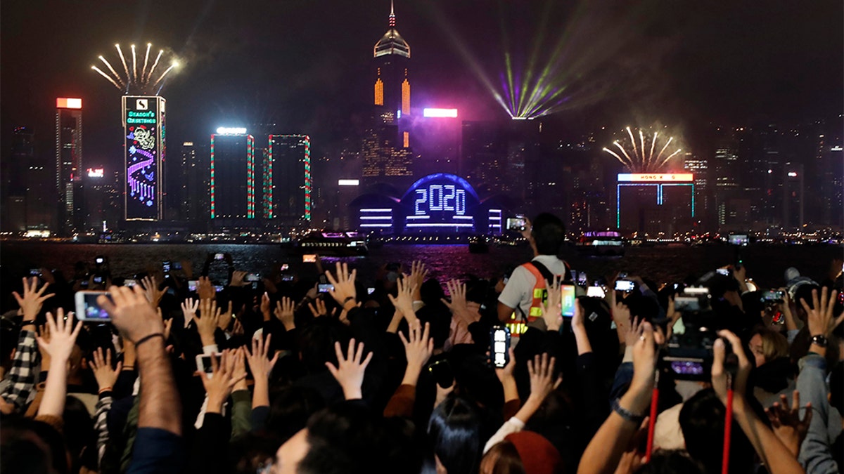Protesters hold up their hands to symbolize the five demands of the pro-democracy movement as New Year's fireworks light up the sky during a demonstration in Hong Kong, Wednesday, Jan. 1, 2020. (Associated Press)