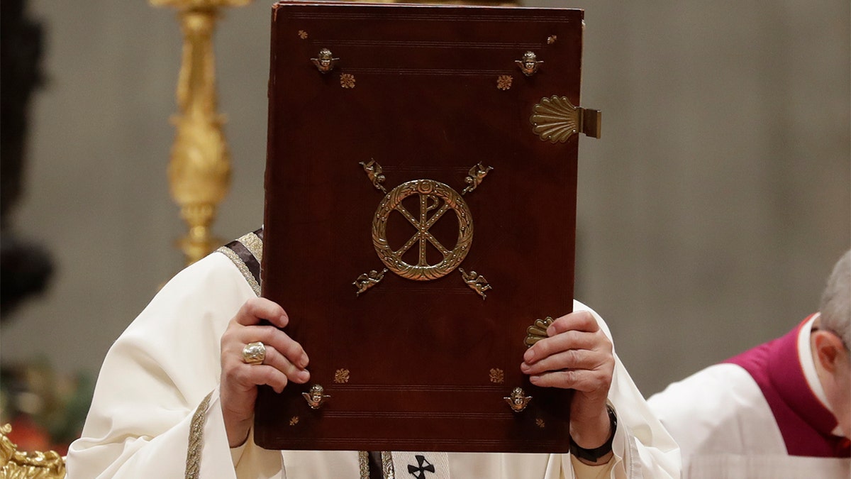 Pope Francis holds up the book of Gospels during Tuesday's Christmas Eve mass. (AP Photo/Alessandra Tarantino)