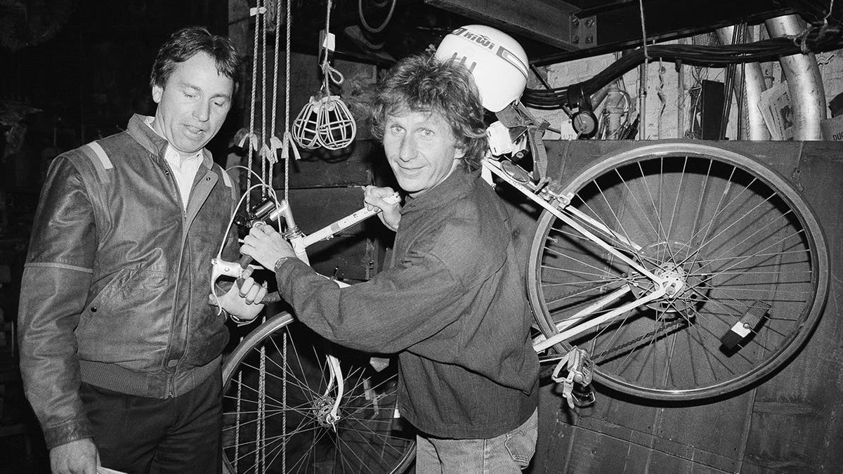 FILE - In this May 16, 1985, file photo, actor John Ritter, left, checks out the bicycle of fellow actor Rene Auberjonois, center, backstage at the Eugene O'Neill Theatre in New York following a performance of the Broadway musical, "Big River: The Adventures of Huckleberry Finn."
