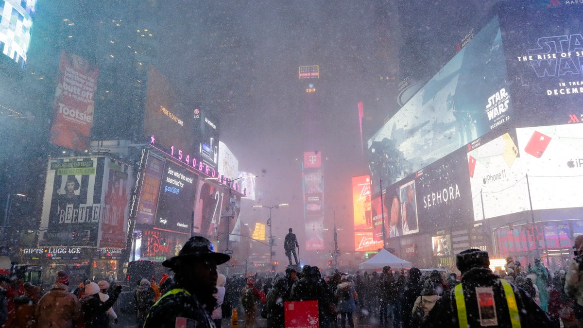 Pedestrians observe a snow squall in Times Square Wednesday, Dec. 18, 2019, in New York.