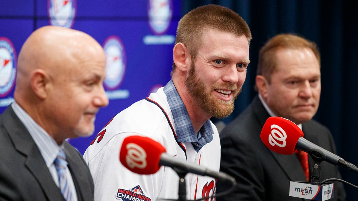 Washington Nationals pitcher Stephen Strasburg, center, speaks during a baseball media availability, accompanied by general manager Mike Rizzo, left, and agent Scott Boras, right, at Nationals Park, Tuesday, Dec. 17, 2019, in Washington. (AP Photo/Alex Brandon)