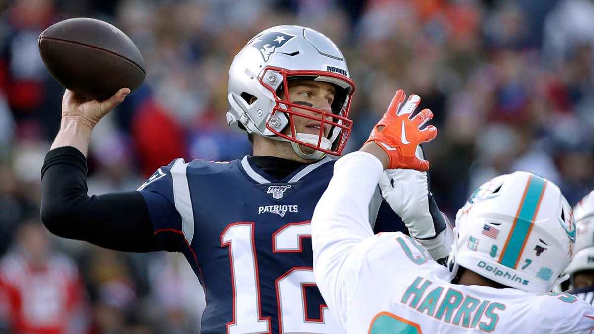 New England Patriots quarterback Tom Brady, left, passing under pressure from Miami Dolphins defensive end Trent Harris Sunday in Foxborough, Mass. (AP Photo/Elise Amendola)