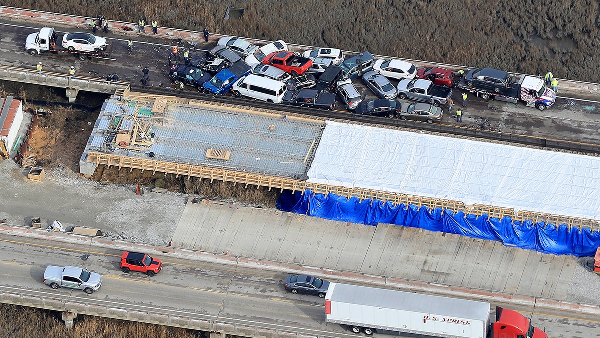 Crews worked to clear vehicles from the Queens Creek overpass on I-64 in York County after a chain-reaction crash involving at least 63 cars. (Rob Ostermaier/The Daily Press via AP)