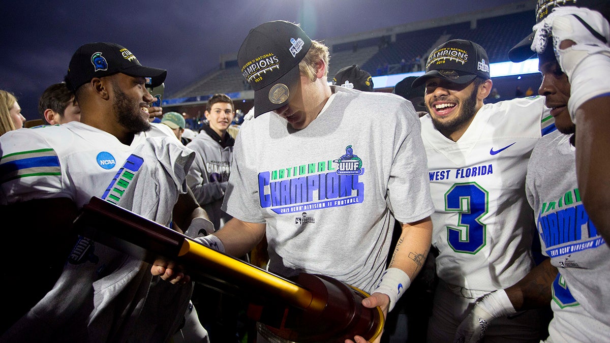 West Florida quarterback Austin Reed, center, holds the trophy while celebrating with teammates after the team won the Division II championship NCAA college football game against Minnesota State, Saturday, Dec. 21, 2019, in McKinney, Texas. (AP Photo/Gareth Patterson)