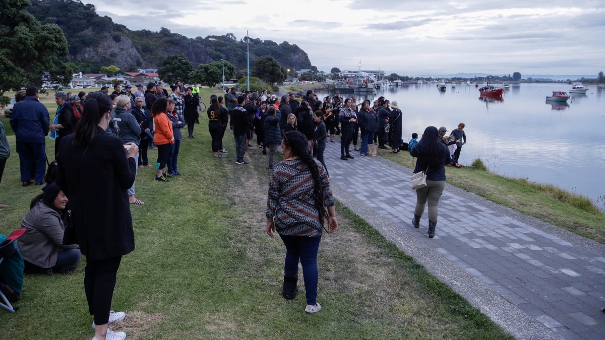 Locals sing during sunrise as they wait for the return of the victims after the White Island eruption to be returned to Whakatane, New Zealand, Friday, Dec. 13, 2019.