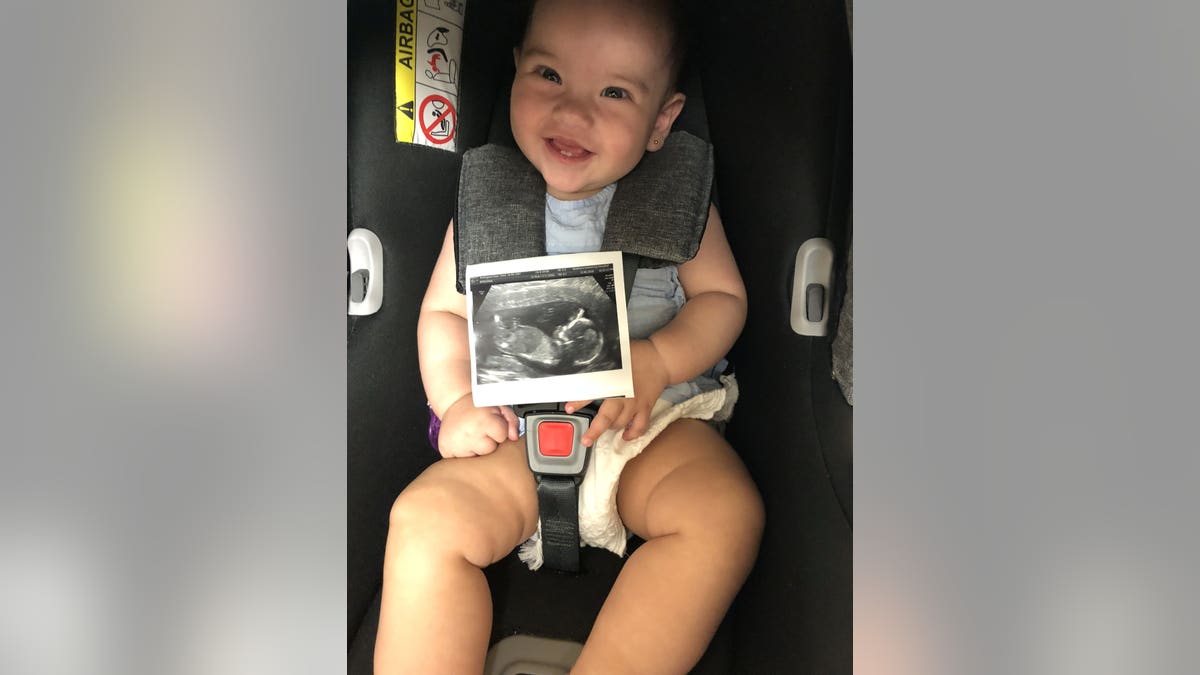 Baby Valentina holding a scan of Santi in the womb.