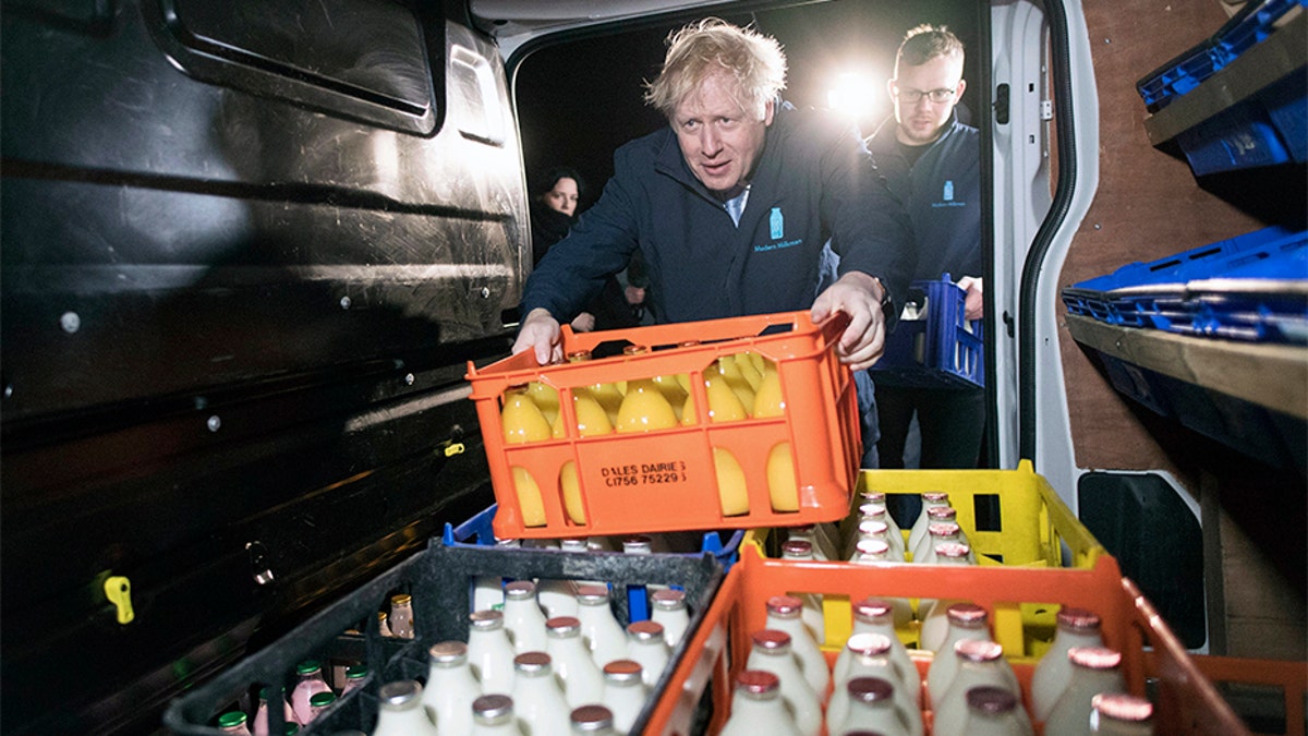 Britain's Prime Minister Boris Johnson loads a crate into a milk delivery van.