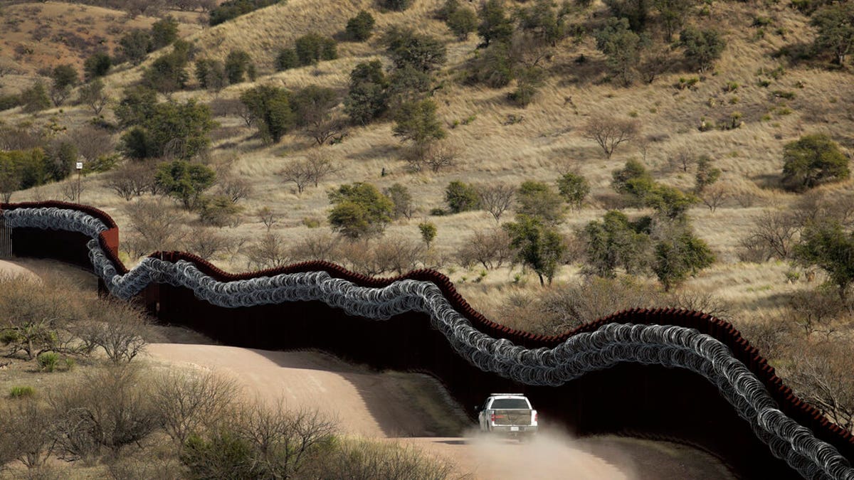 A Customs and Border Control agent patrols on the US side of a razor-wire-covered border wall along the Mexico east of Nogales, Ariz. 