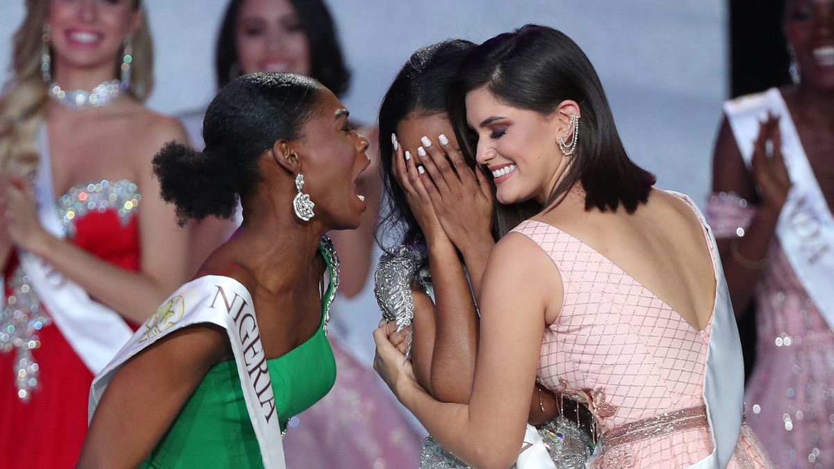 Miss Nigeria, left, shouts with excitement at Miss Jamaica, center, for winning the Miss World 2019 crown. Miss Brazil, right, also embraces the winner with a hug.
