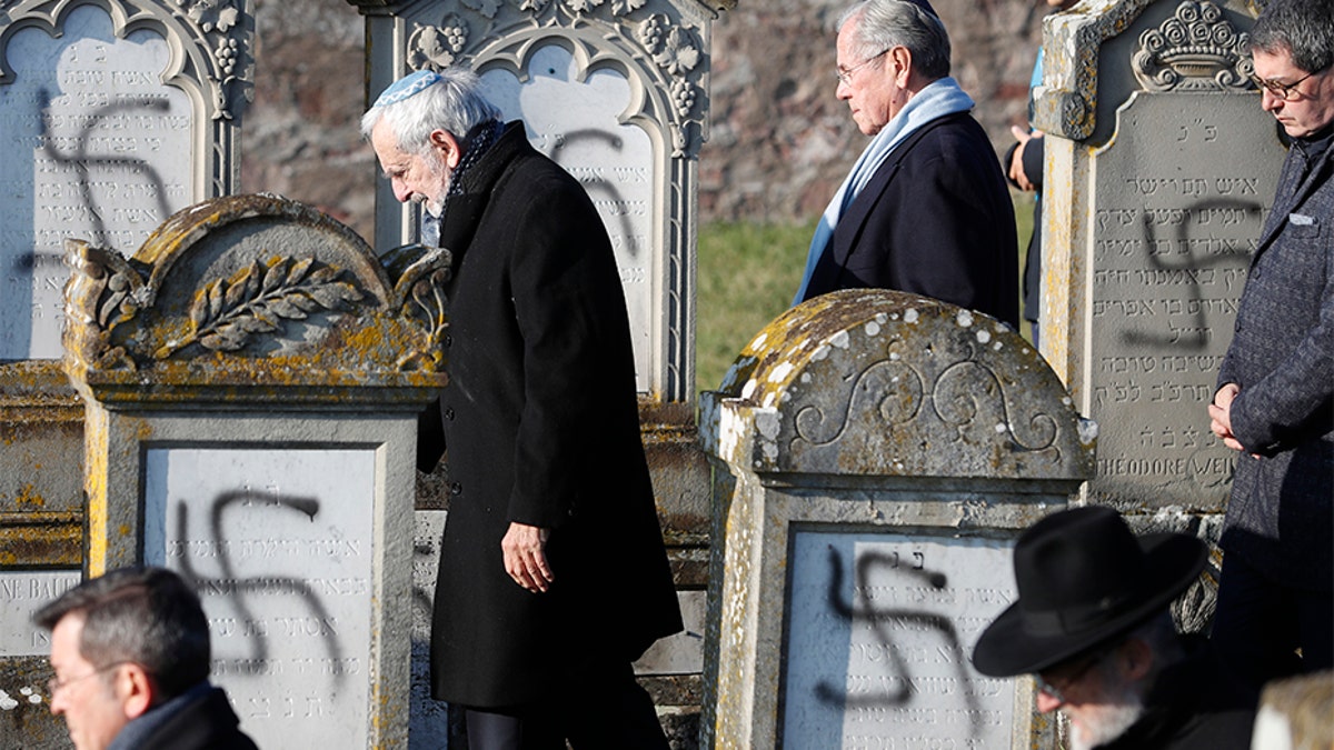 Members of the Jewish community walk amid vandalized tombs in the Jewish cemetery of Westhoffen, west of the city of Strasbourg, on Wednesday. (AP)