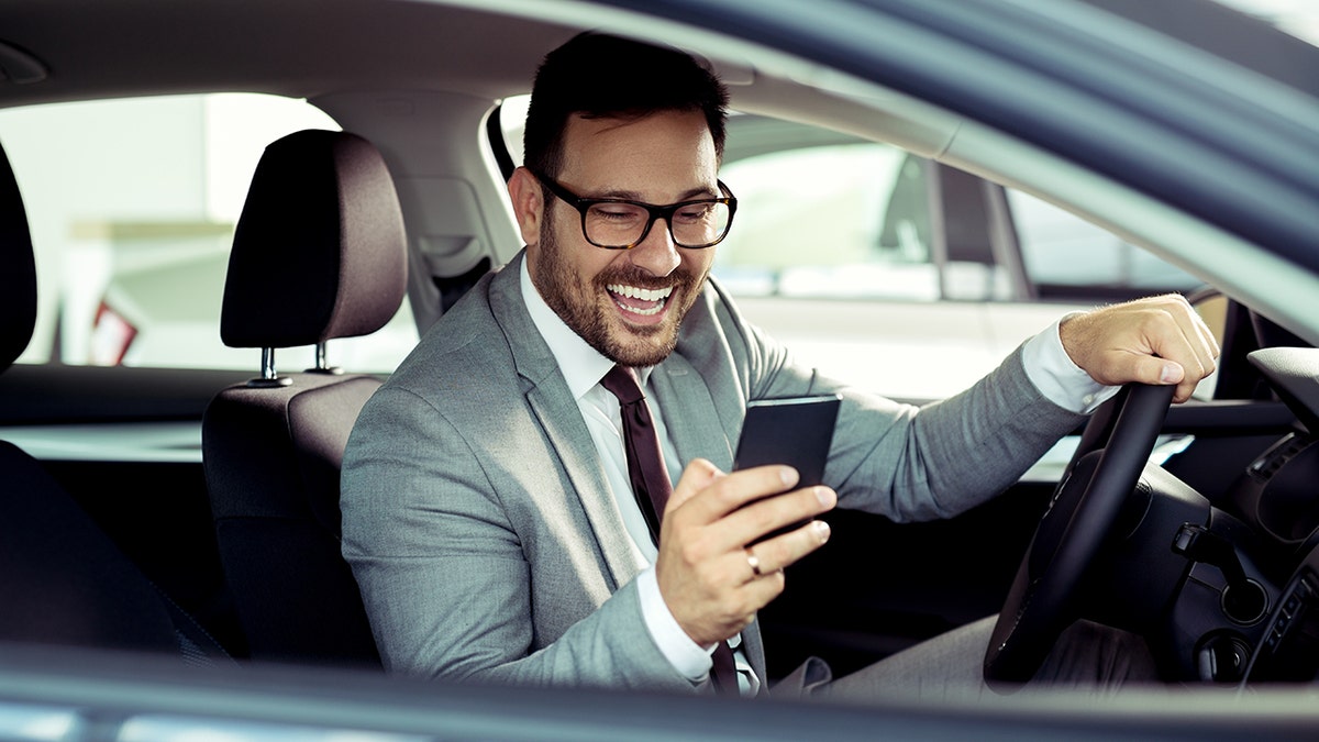 Man uses smartphone in his car.