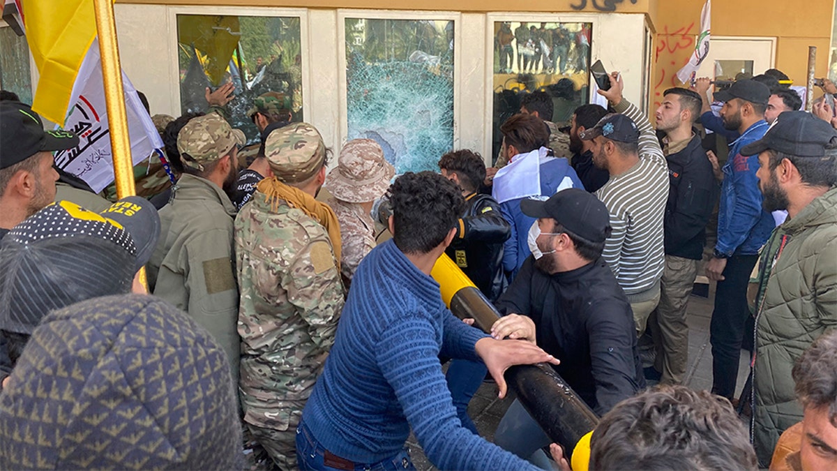 Protesters smash a window inside the U.S. embassy compound in Baghdad on Tuesday. (AP)