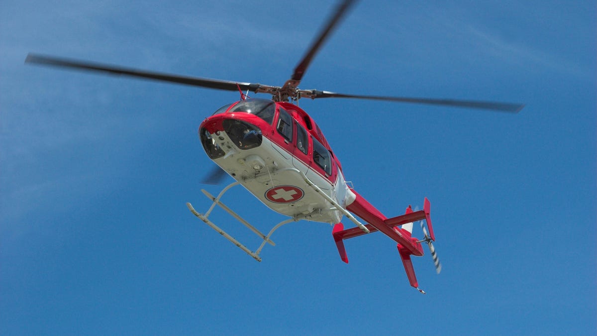 Closeup of flying red helicopter in contrast with blue sky