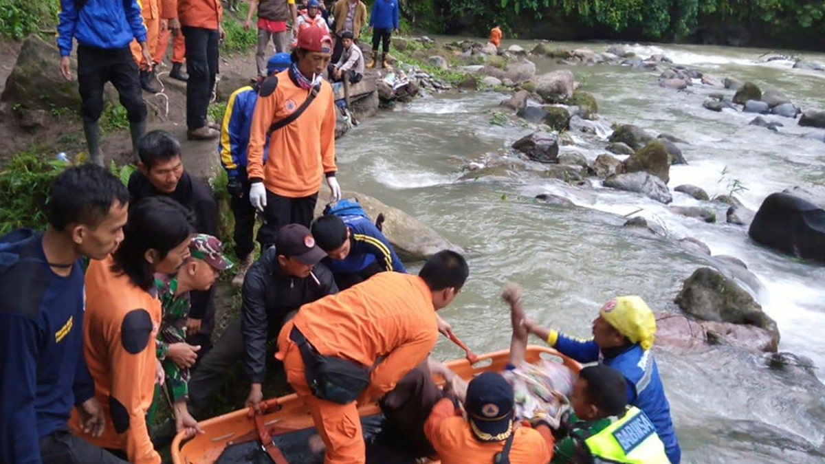 In this photo released by the National Search And Rescue Agency (BASARNAS), rescuers remove the body of a victim of a bus accident in Pagaralam, Indonesia, Tuesday, Dec. 24, 2019. A number of people were killed when the passenger bus plunged into the ravine on Sumatra island after its brakes apparently malfunctioned, police said Tuesday. (BASARNAS via AP)