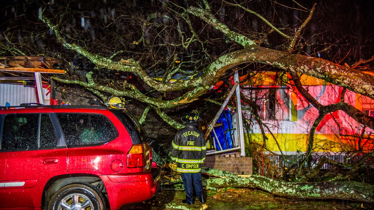 Cory Simpson of Decatur Fire &amp; Rescue assess damage before evacuating a mobile home after a tree fell on the home in Decatur, Ala., on Dec. 16, 2019.