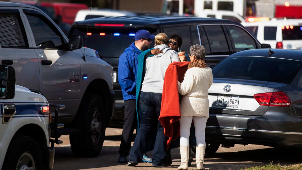 Residents embrace near police and fire cars that surround the scene of a shooting at West Freeway Church of Christ in White Settlement, Texas, Sunday, Dec. 29, 2019.