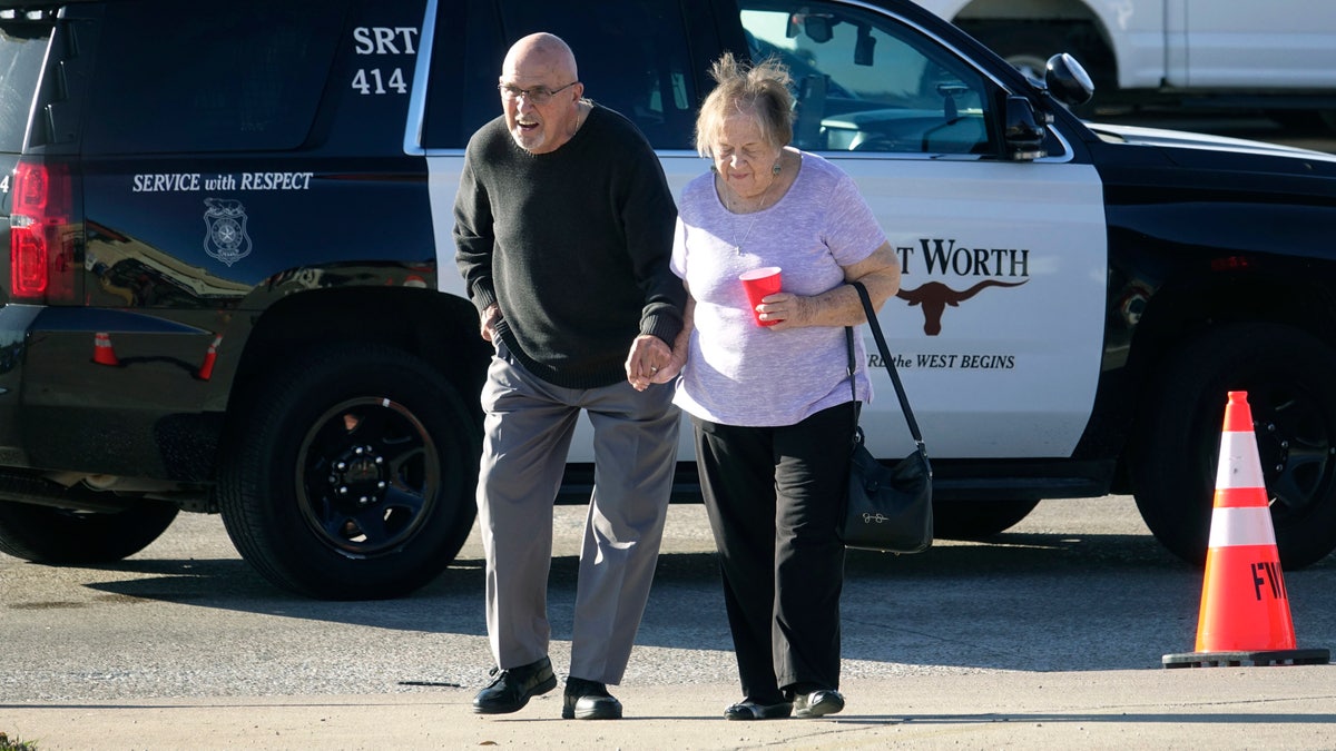 An elderly couple walks from West Freeway Church of Christ hours after a fatal shooting at the church, Sunday, Dec. 29, 2019, in White Settlement, Texas.