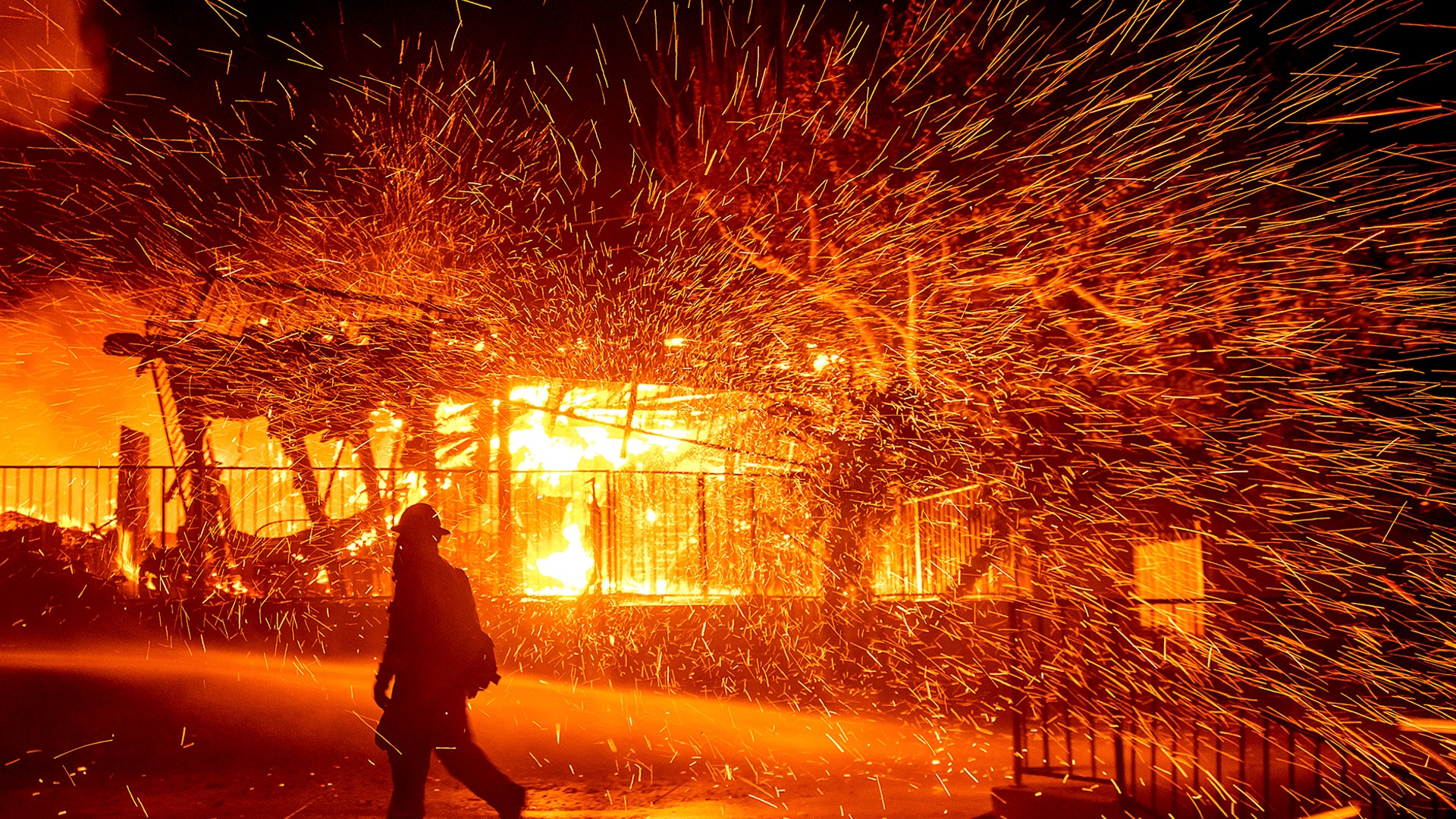 A firefighter passes a burning home as the Hillside fire burns in San Bernardino, California, Oct. 31, 2019. 
