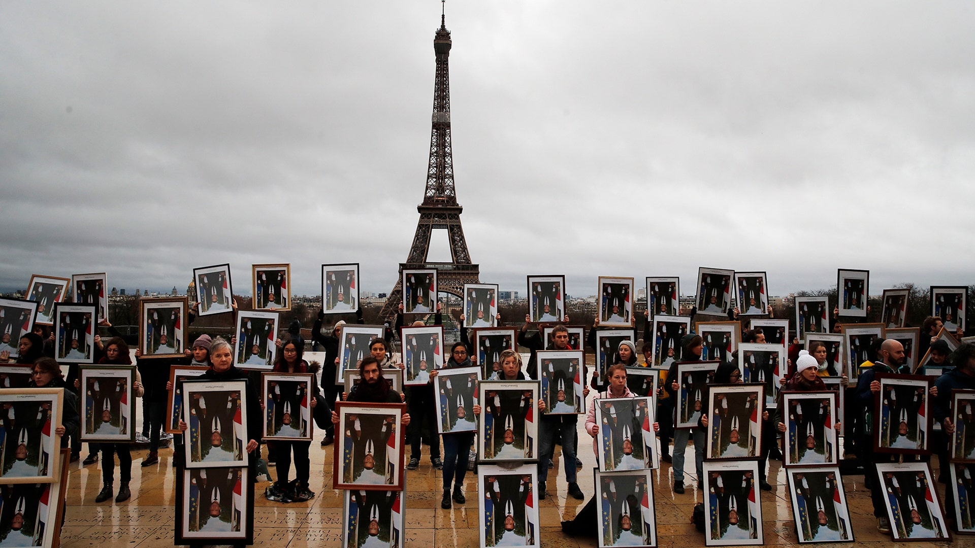 A hundred activists hold portraits of President Emmanuel Macron upside down to urge France to take action during the U.N. COP 25 climate during a gathering at Place du Trocadero in Paris, Dec. 8, 2019. 