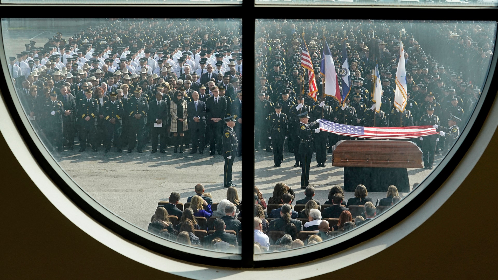 Police Honor Guard members framed through a window of Grace Church, fold a flag during the funeral of Houston Police Sgt. Christopher Brewster, in Houston, Dec. 12, 2019. 