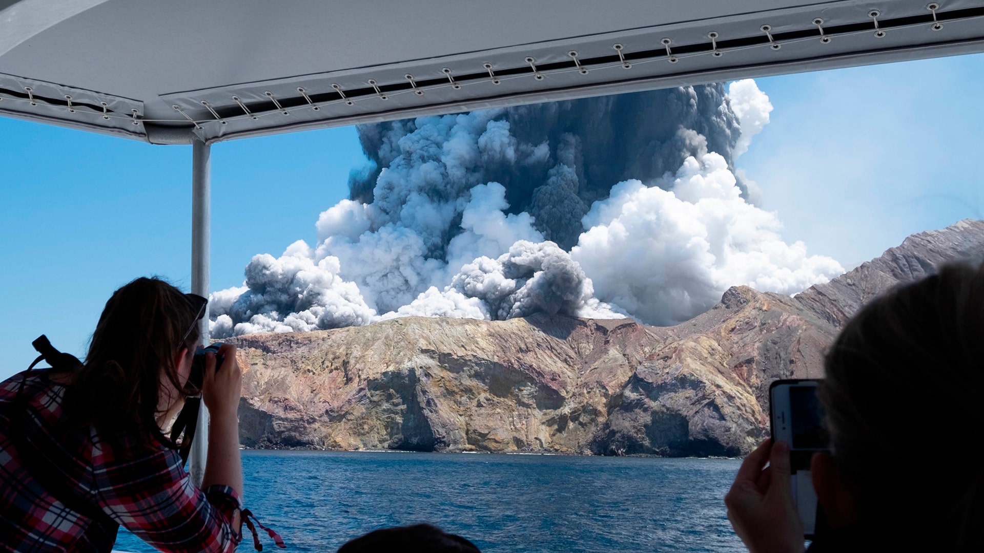 Tourists on a boat photograph the eruption of the volcano on White Island, New Zealand, Dec. 9, 2019. 