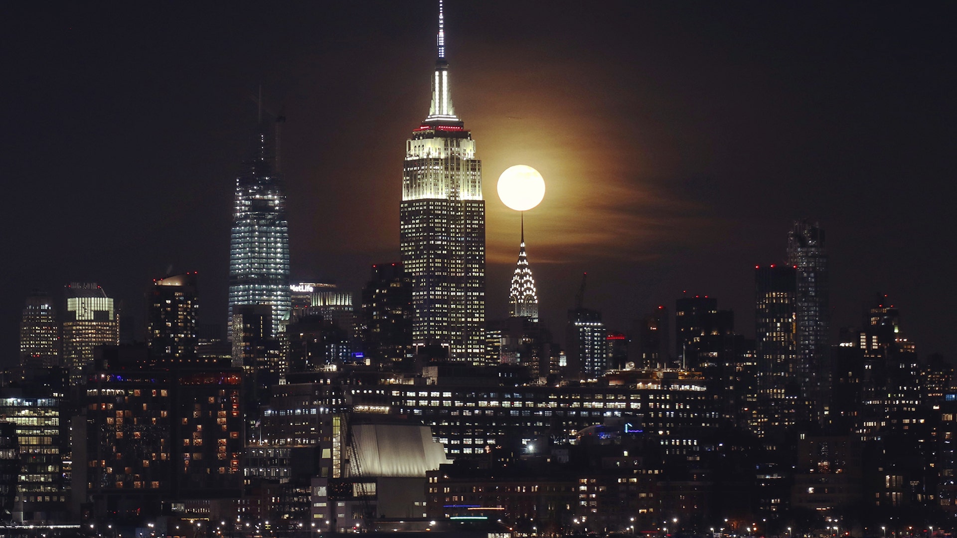 The full Cold Moon rises behind the Empire State Building and Chrysler Building in New York City, Dec. 12, 2019.