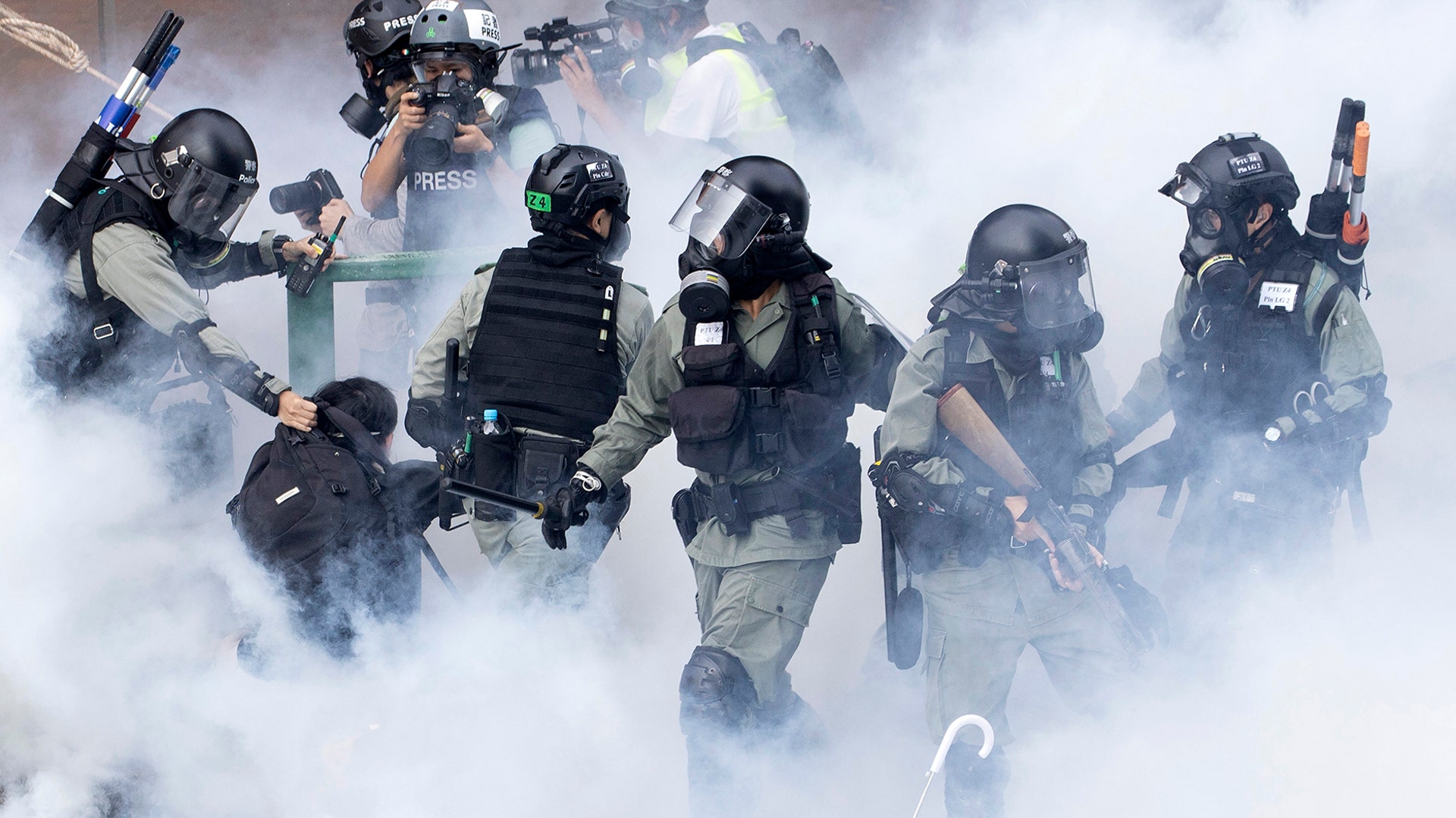 Police in riot gear move through a cloud of smoke as they detain a protester at the Hong Kong Polytechnic University in Hong Kong, Nov. 18, 2019. 